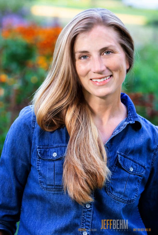 portrait by Frederick portrait photographer, Jeff Behm, woman in blue denim shirt with long dark blond hair, outdoors in field of flowers