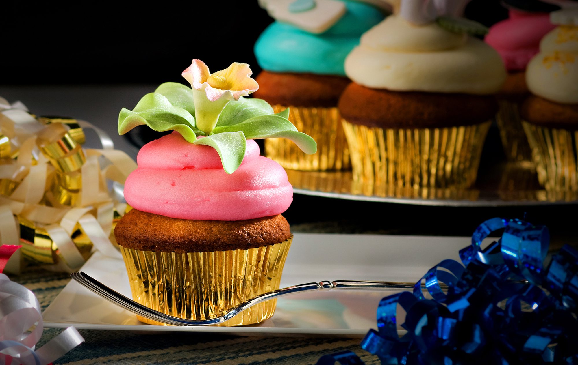 Strawberry iced cupcake with sugar flower decoration in party setting